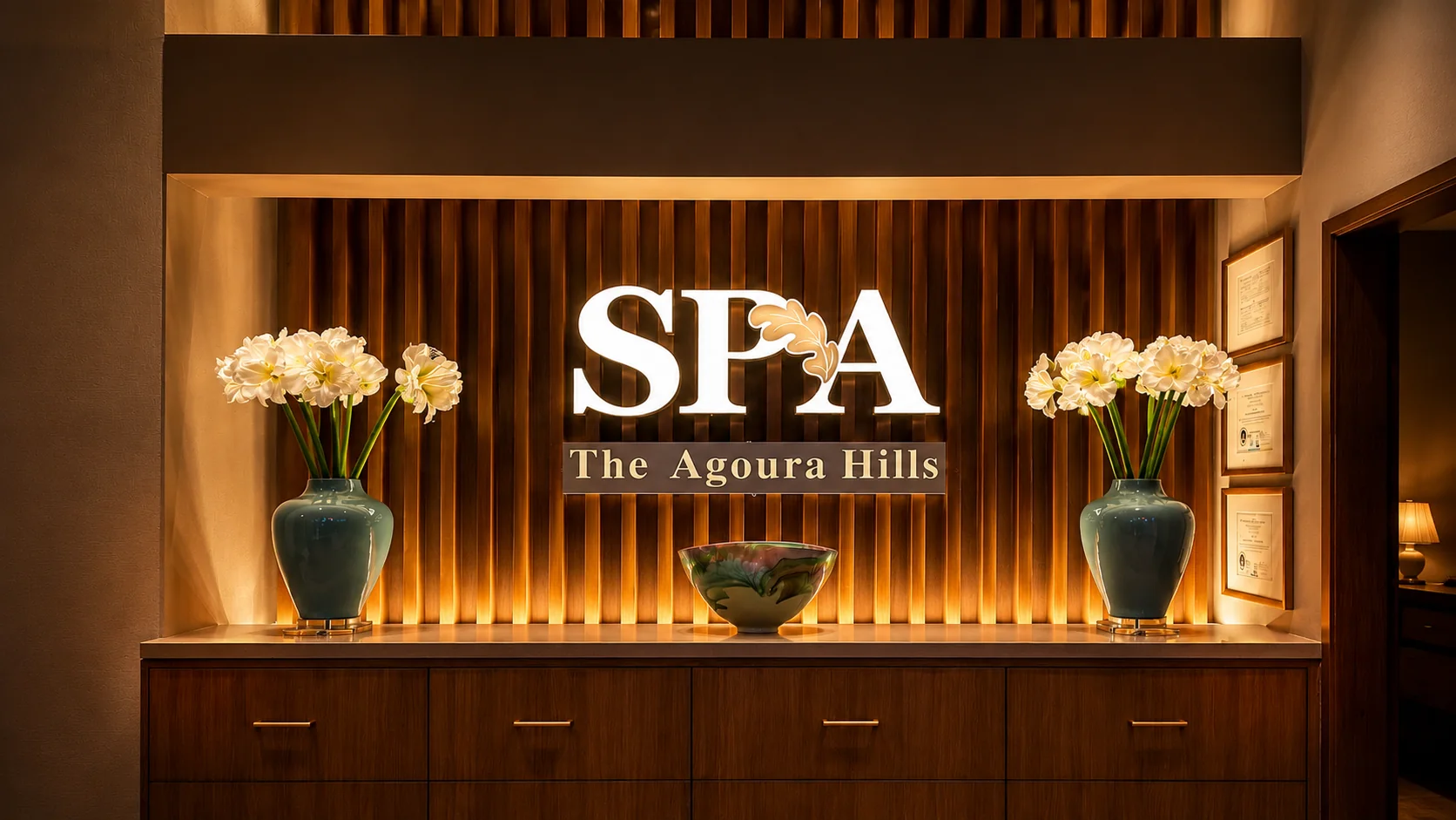 Backlit gold SPA — The Agoura Hills sign on a slatted wood feature wall with amaryllis flower vases